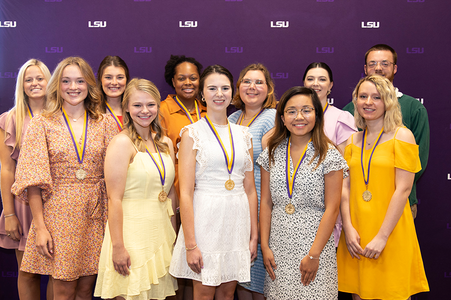 group of 11 students standing in front of purple background.