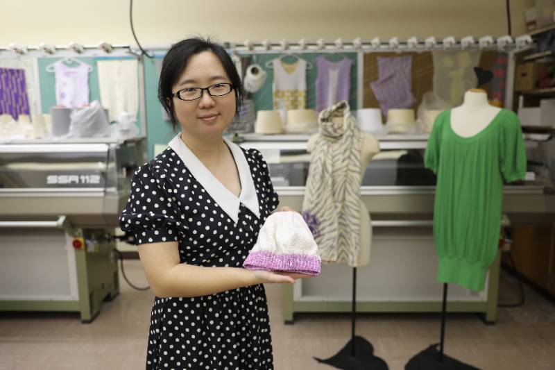 Sibei Xia stands holding textile she developed to detect fevers