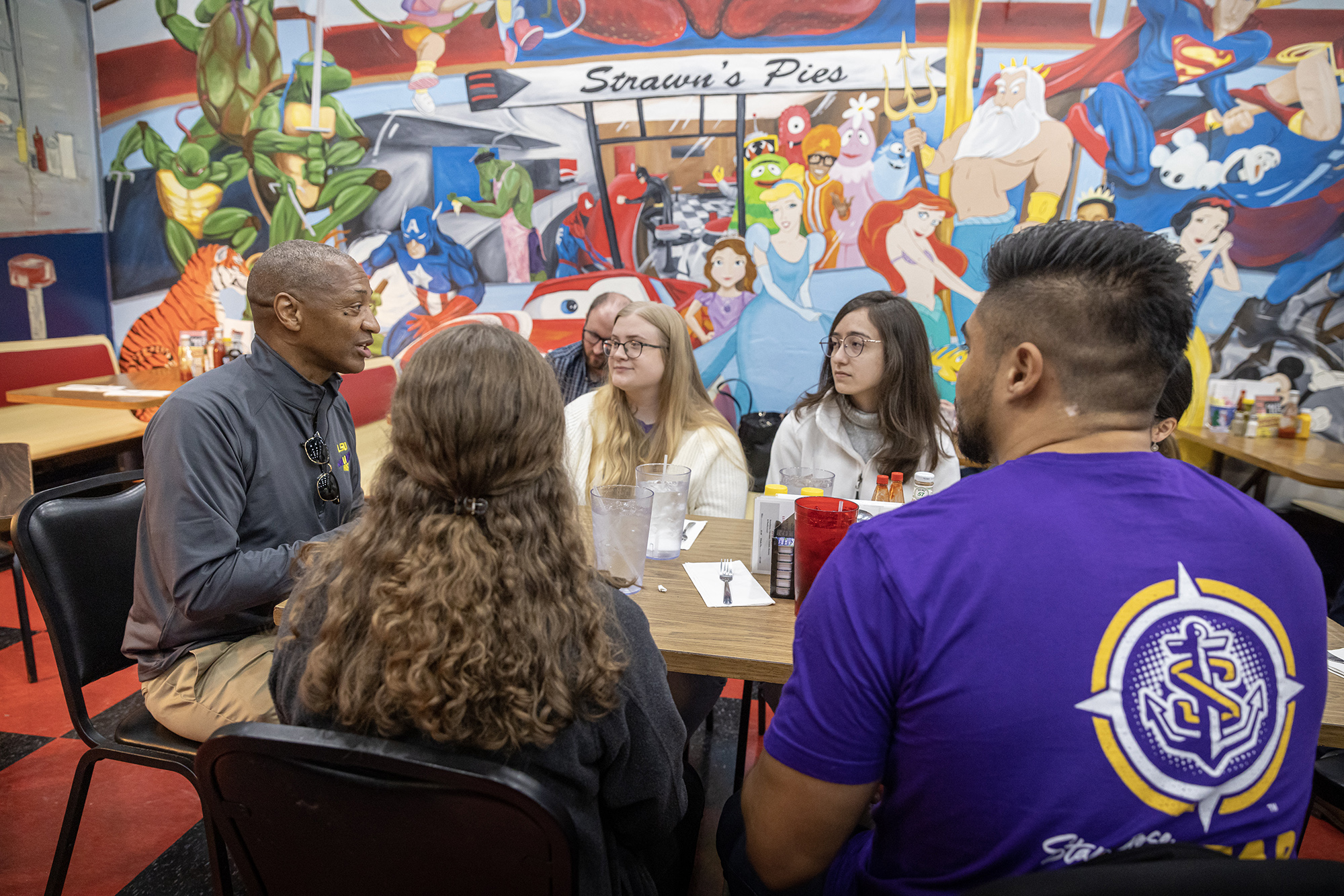President Tate speaks with students at a table