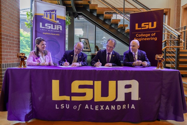 LSU Alexandria and LSU College of Engineering officials sign partnership documents at table draped with LSUA cloth sign with LSUA and LSU Engineer banners in the background