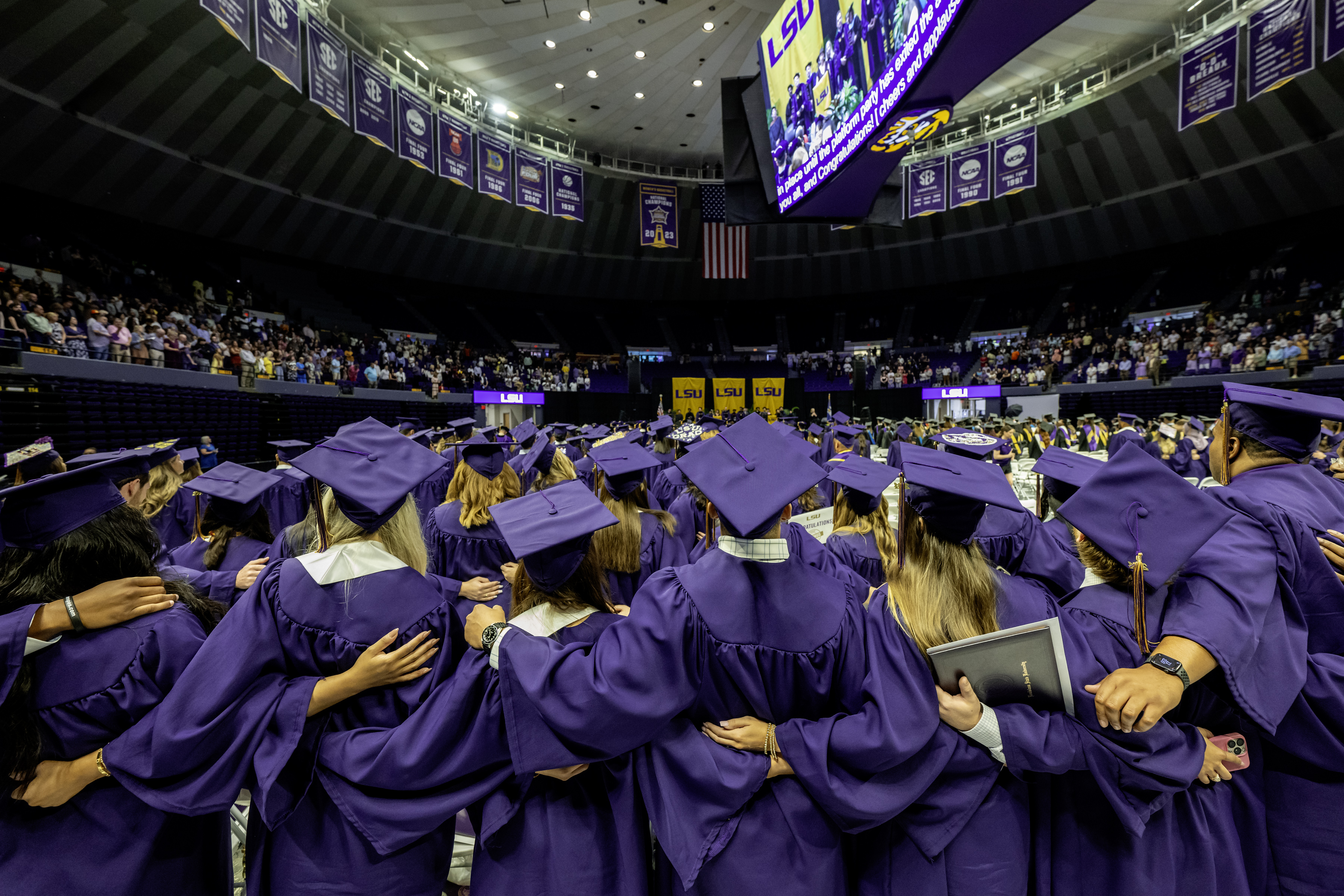 Graduates share a group embrace during LSU's summer commencement