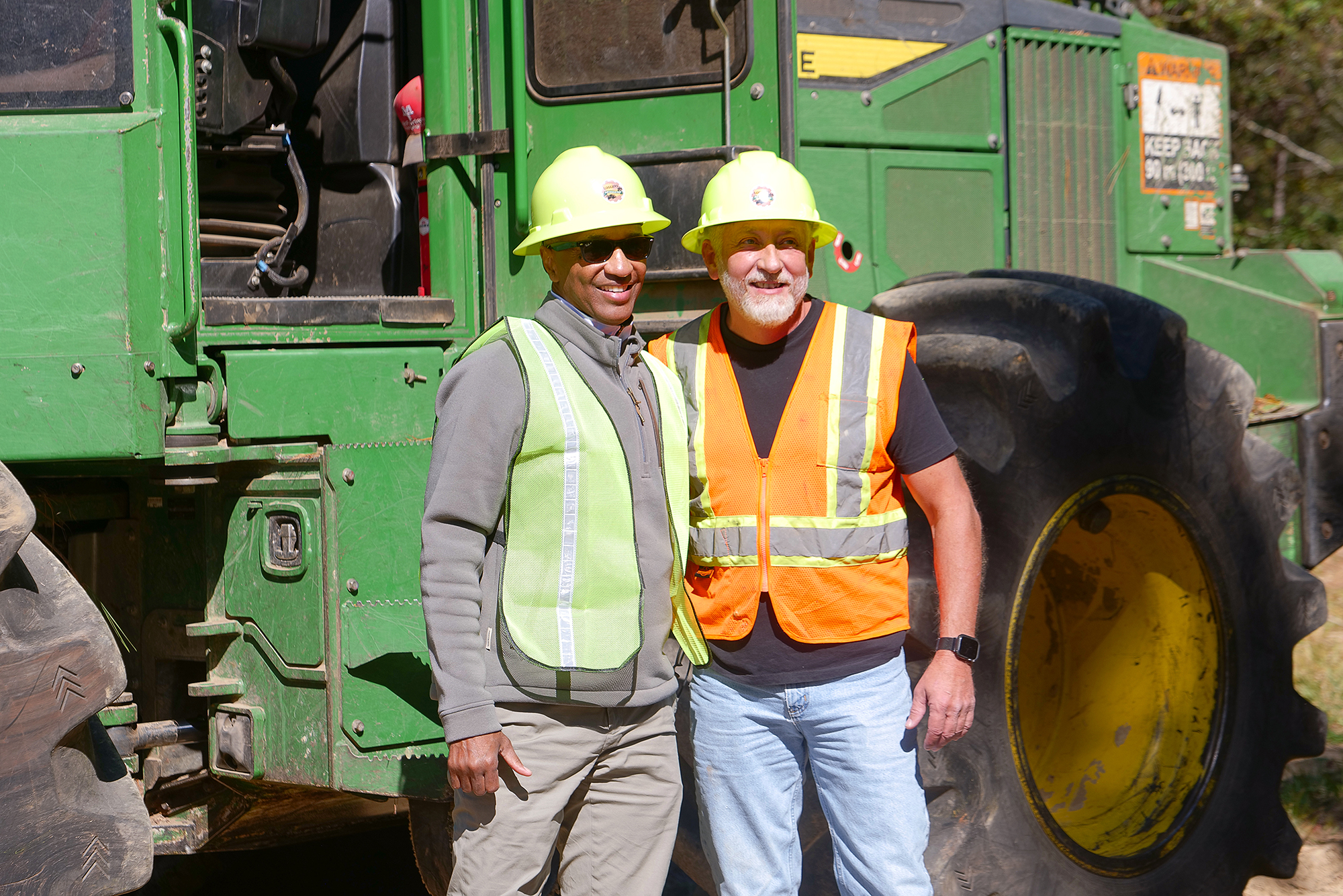  President Tate and Rep. Jack McFarland pose in front of logging equipment