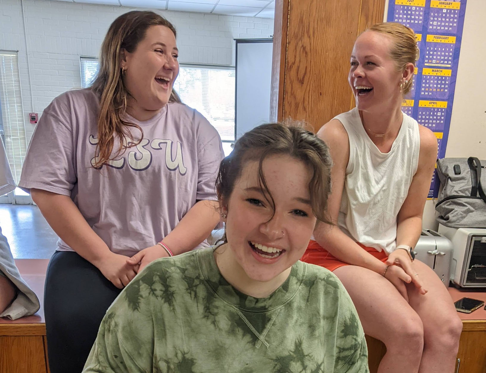 Three students share a laugh while participating in a cooking lesson.