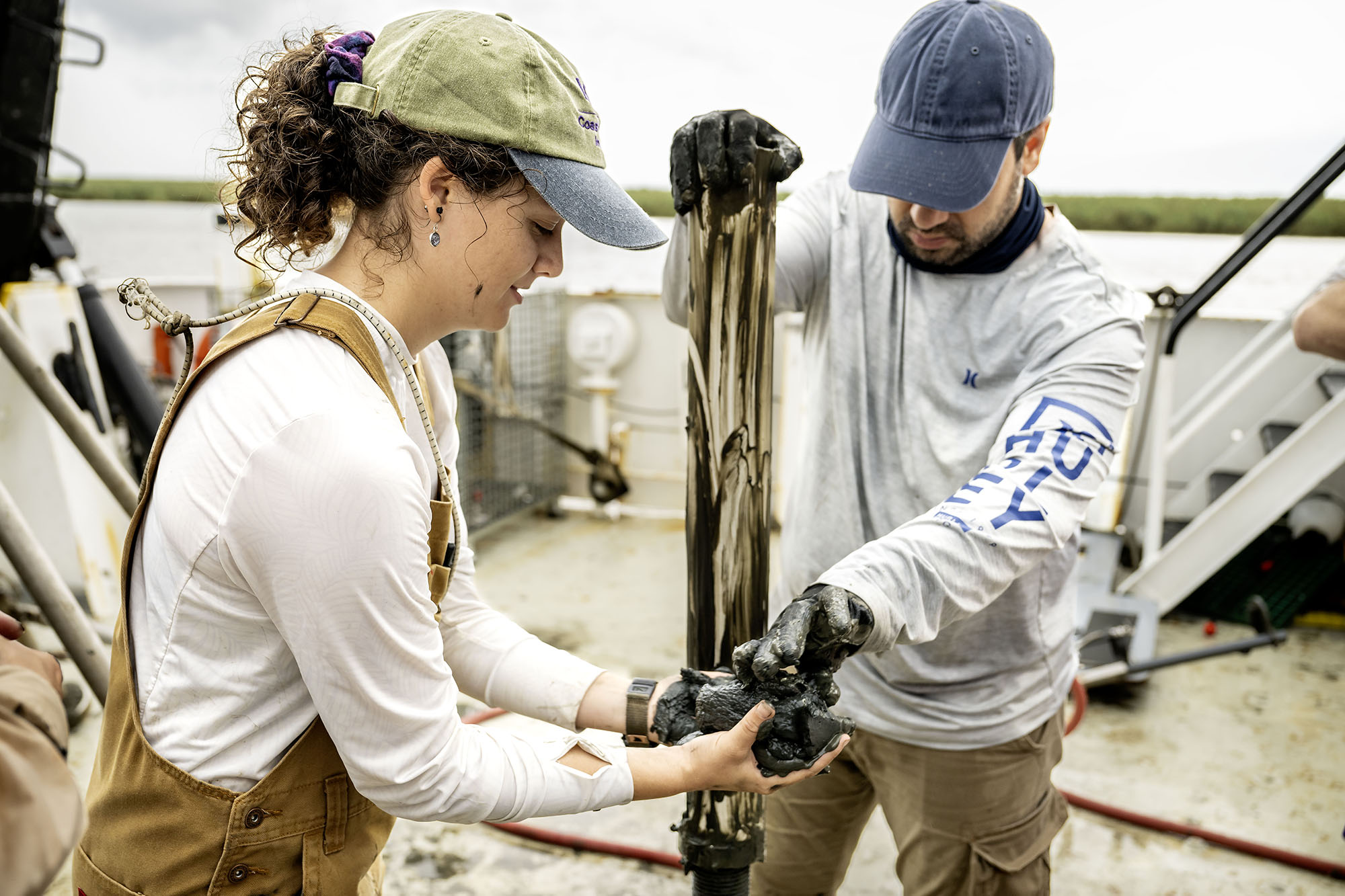 Researchers work with a core sample of settlement on the deck of the research vessel.