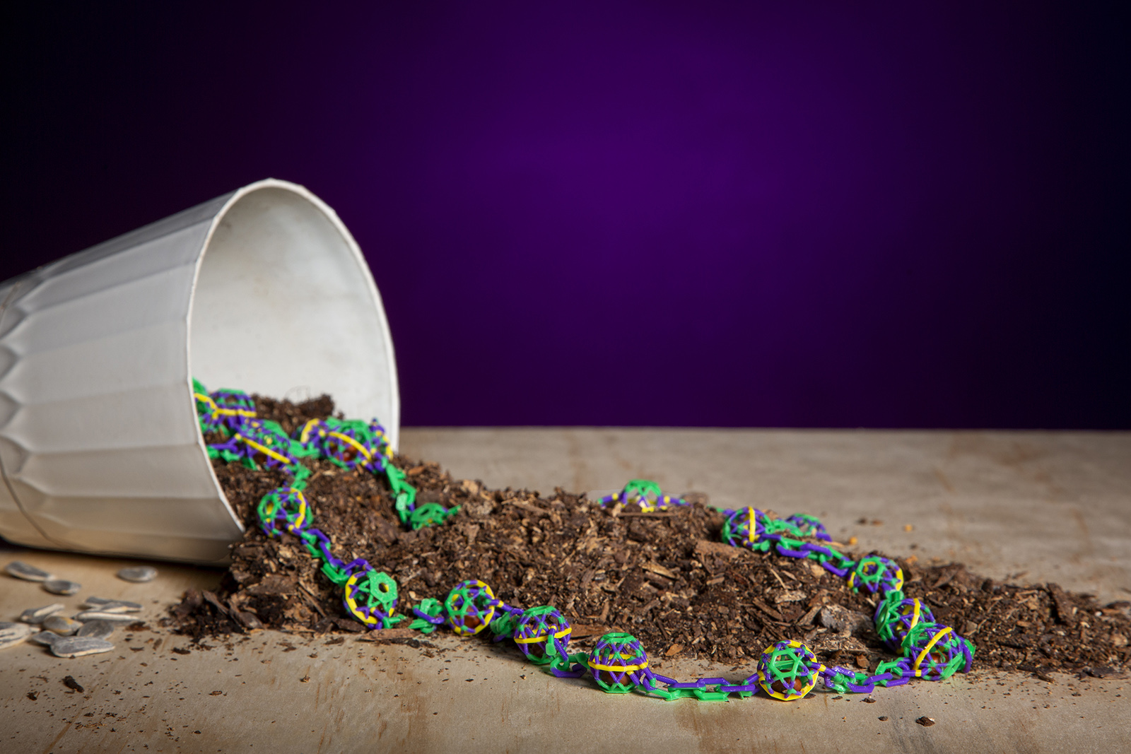 Biodegradable beads and dirl spill from an overturned pot.