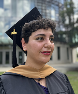 Zarah's headshot taken from the side, she wears a cap and gown and stands in the BEC courtyard on a sunny day.