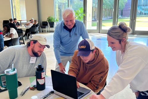 Three students work together at a round table in the BEC while Stephen Hightower leans in to provide guidance.