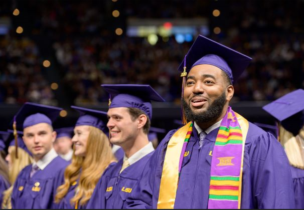 Group of graduates in cap and gowns smiling.