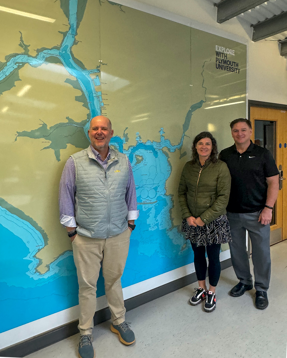 three people stand in front of a map