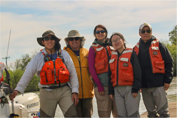 Five people outdoors in life vests and waders