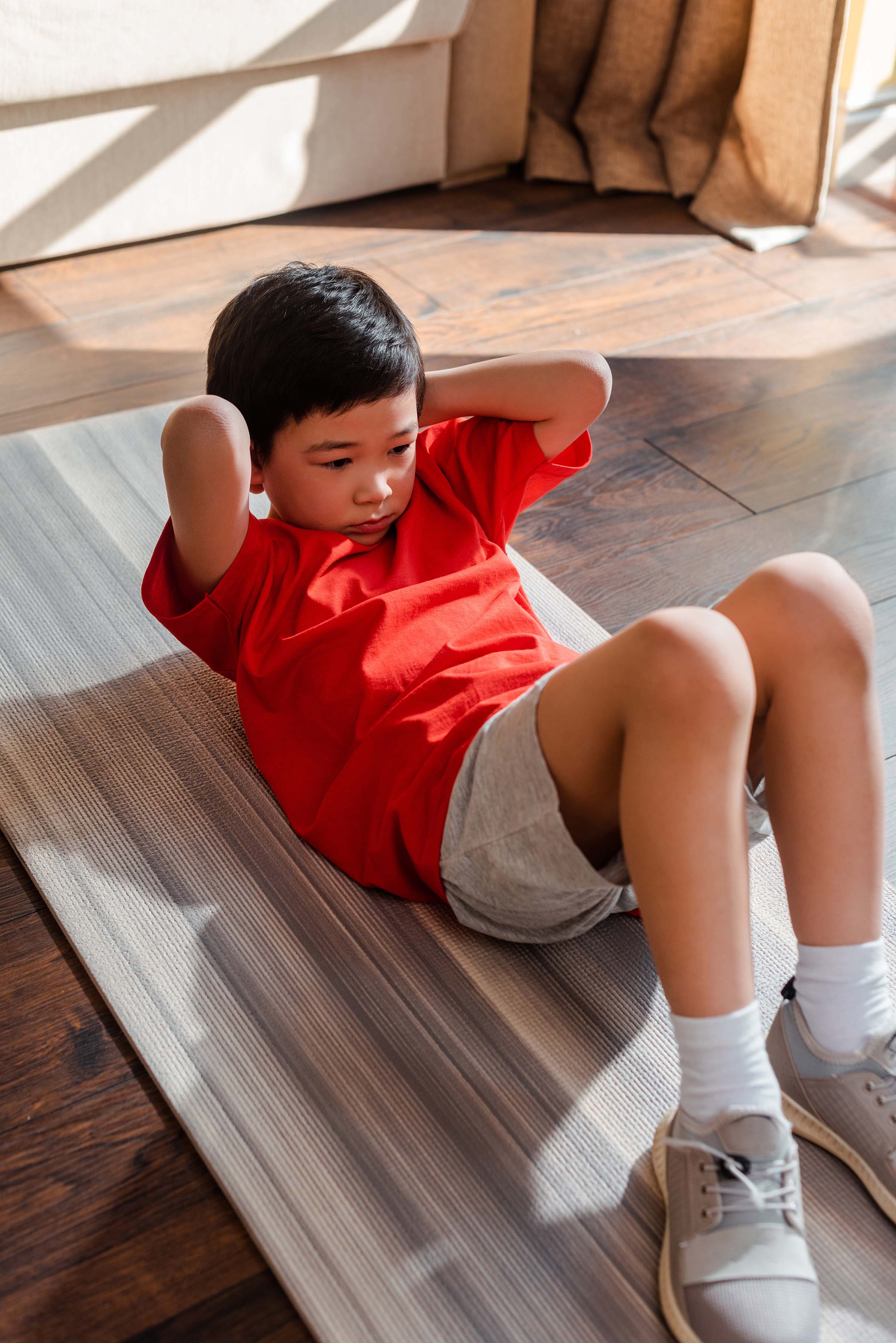 Asian boy doing sit ups in his home