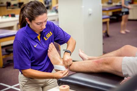 female athletic trainer student bandaging ankle