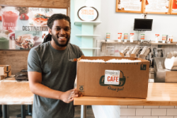 Photo of Tropical Smoothie employee with the box of donated food
