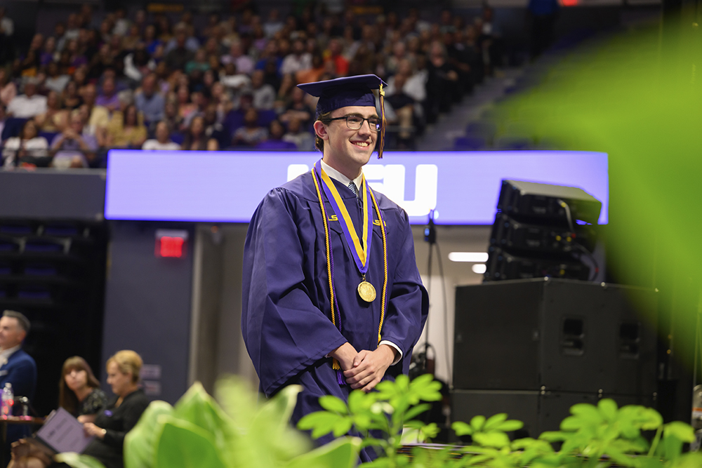 Joshua McCain walks across the stage at graduation