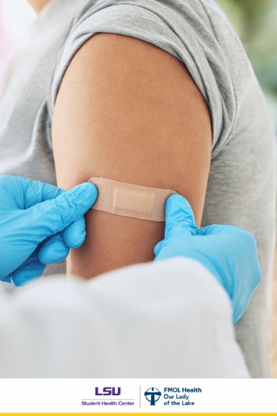 healthcare provider with blue nitrile gloves applying adhesive bandage to a patient's arm