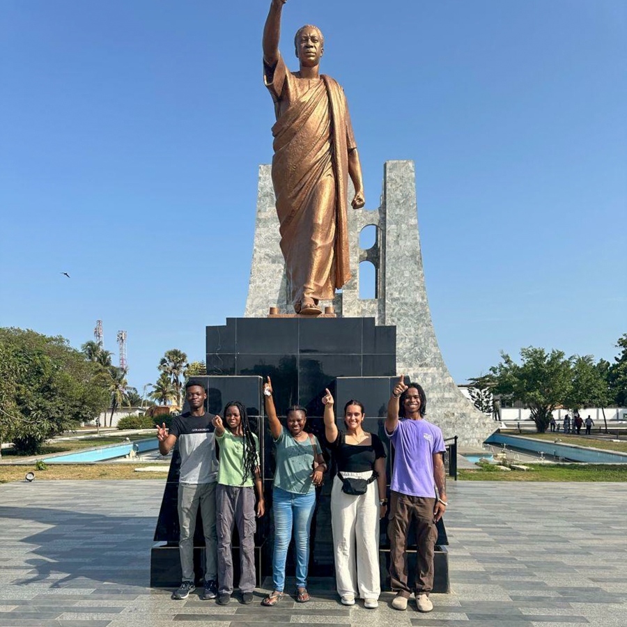 students pose in front of a large golden statue