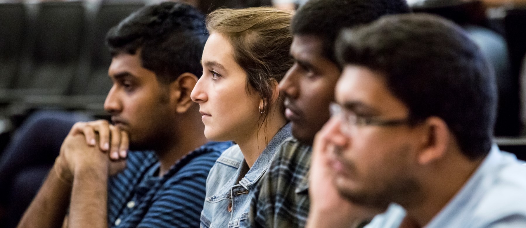 a row of students listen intently to a classroom presentation