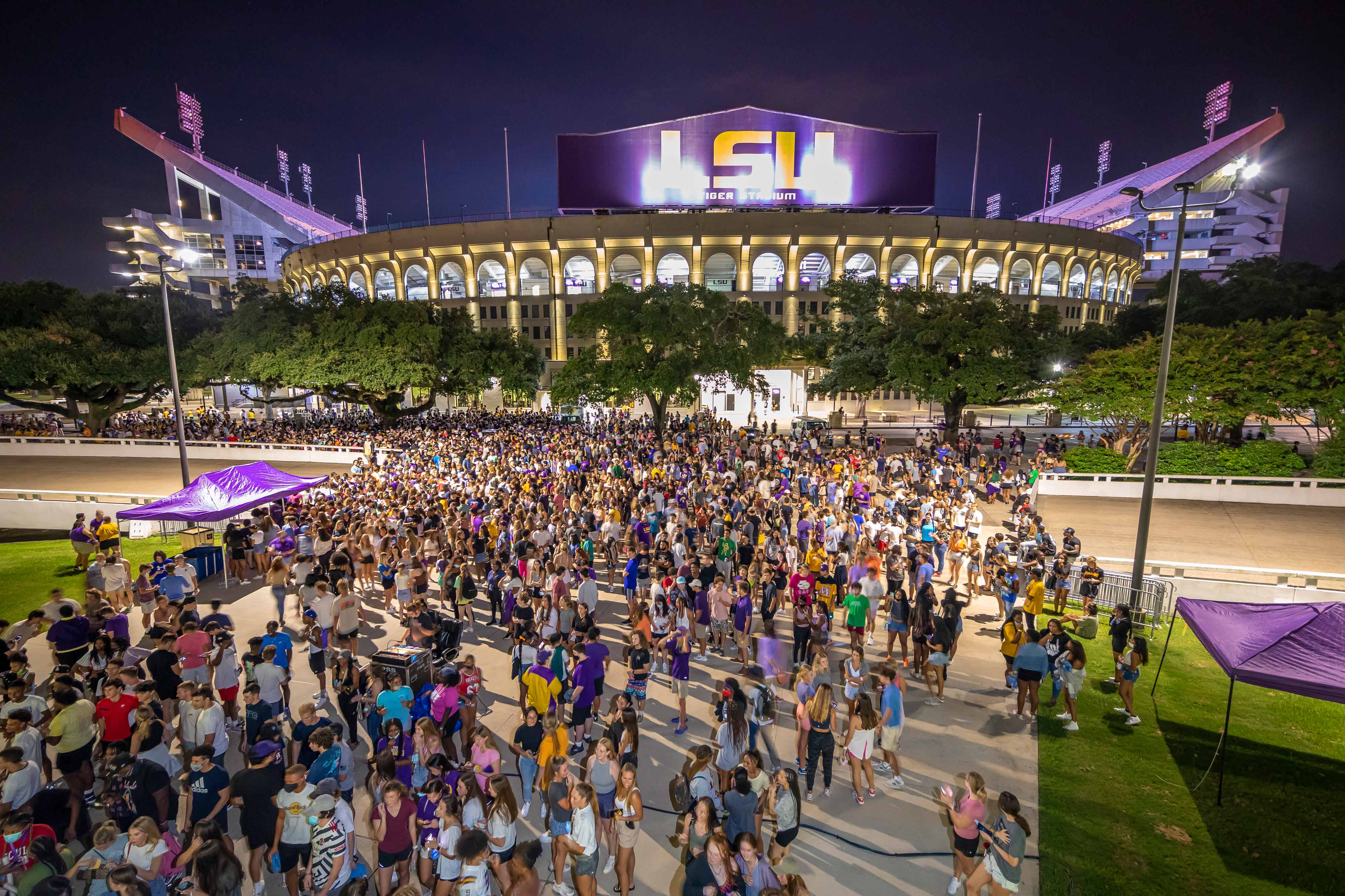 Students gathering at annual block party with Tiger Stadium in background. 