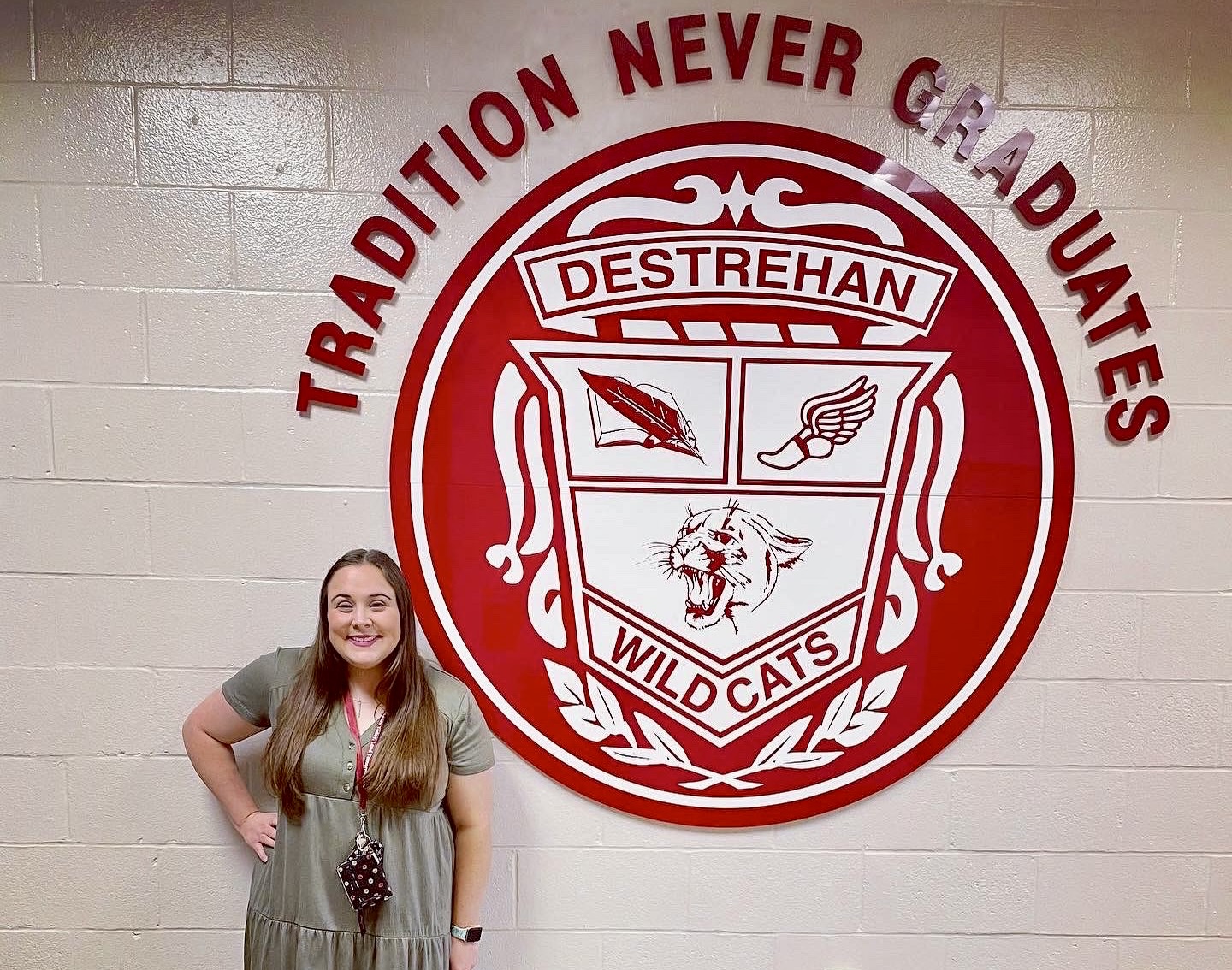 Macy in the hallway posing in front of Destrehan High insignia