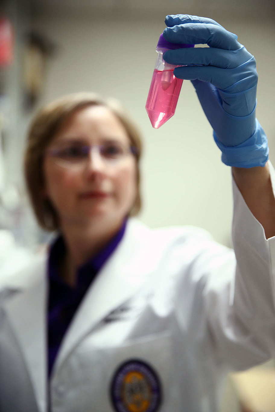 Dr. Stephania Cormier in her lab holding up a tube of pink liquid that containts dissociated cells from lungs.