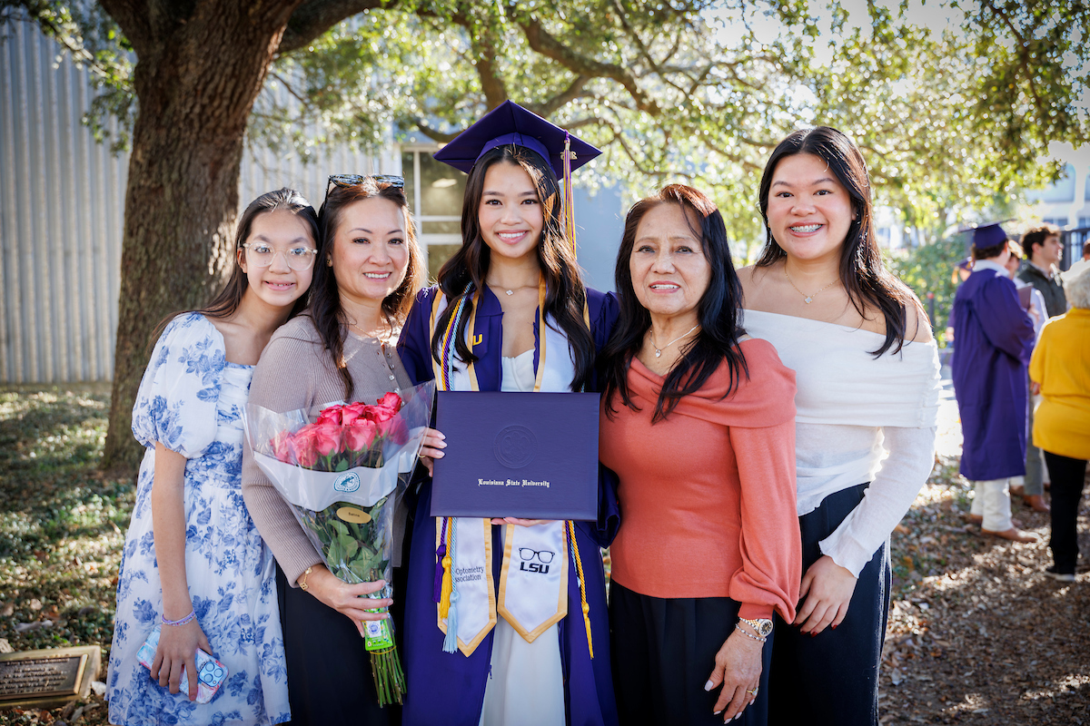 family poses with first-gen student wearing light blue first-gen grad cord