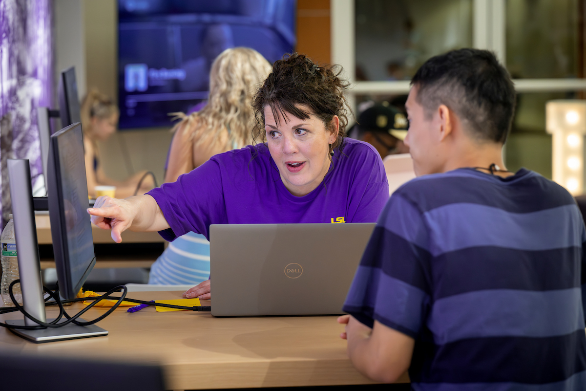 staff member helps a student on a computer