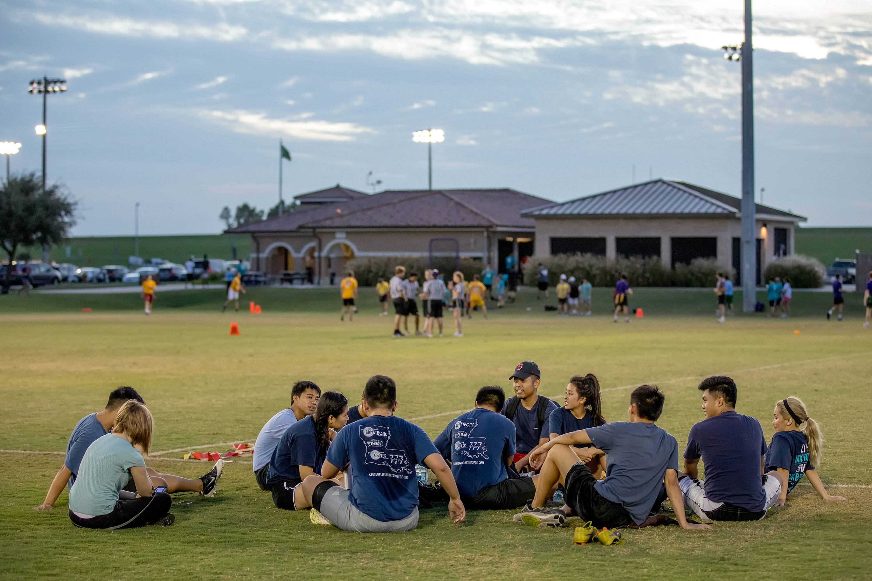 students sitting in the grass at our River Road Field Complex